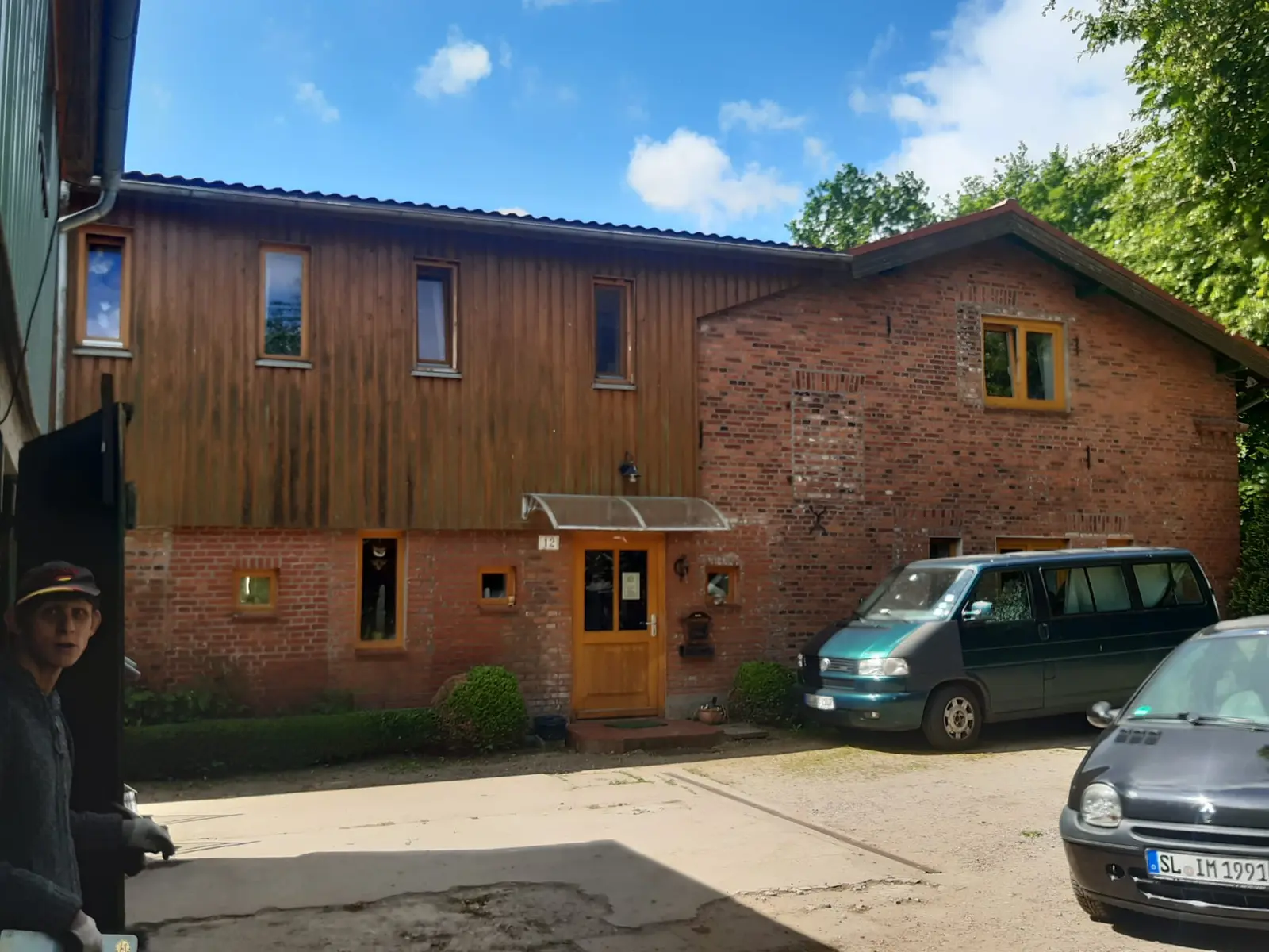 Das historische Hofhaus mit Holzfassade und einem grünen Garten